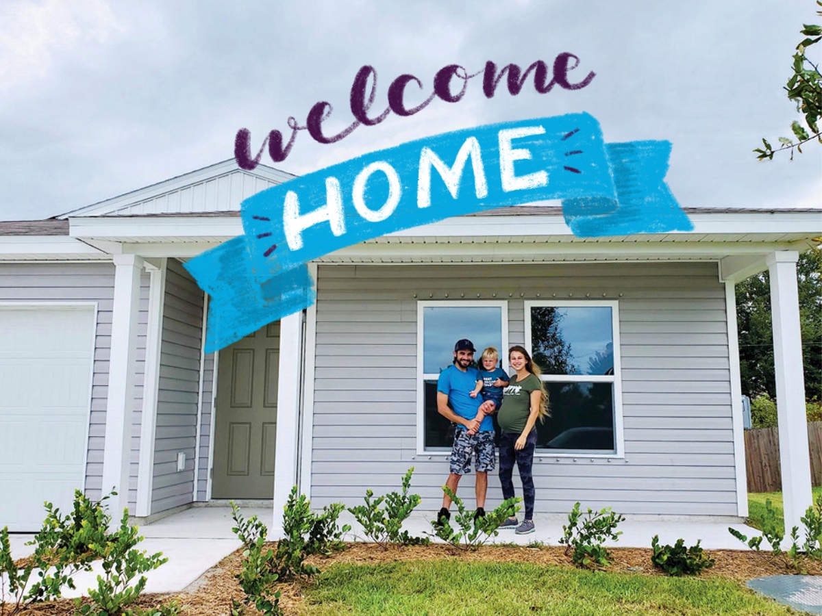 A man and woman standing in front of a building with a sign.