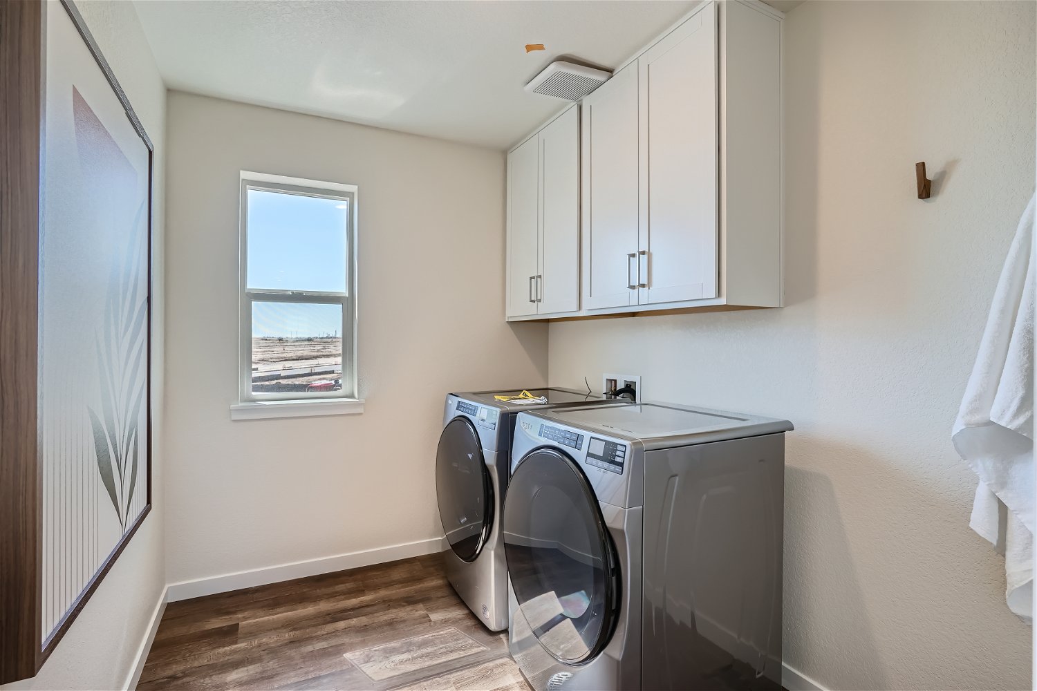 A laundry room with white cabinets.