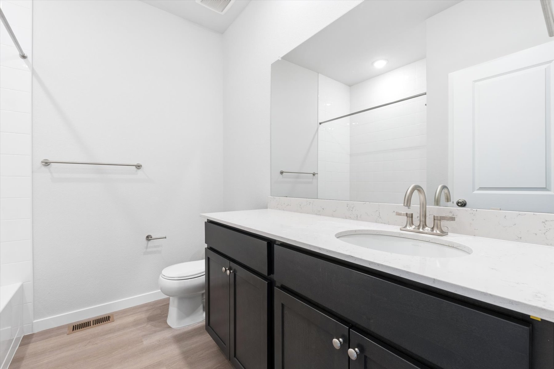 A bathroom with a sink toilet and mirror.