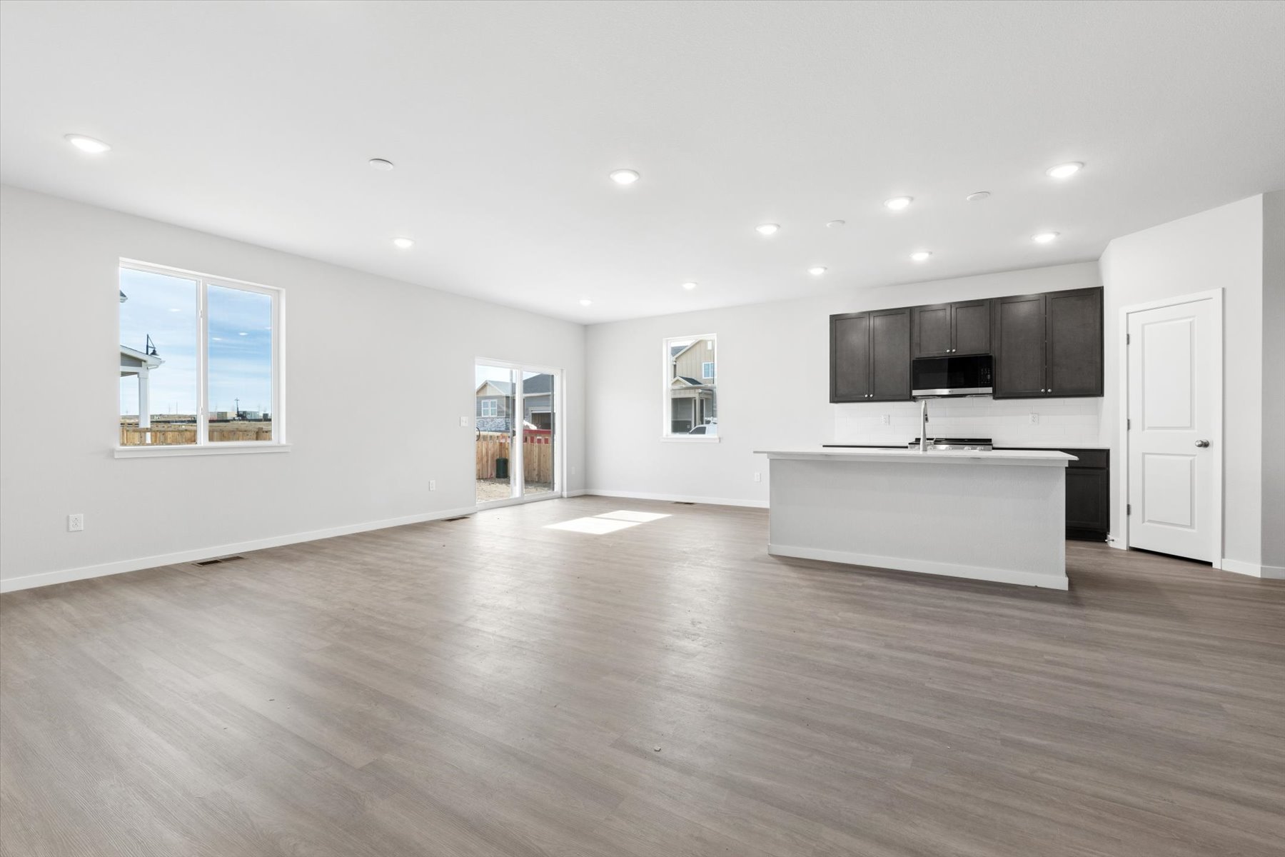 A large empty room with a large white kitchen and black cabinets.