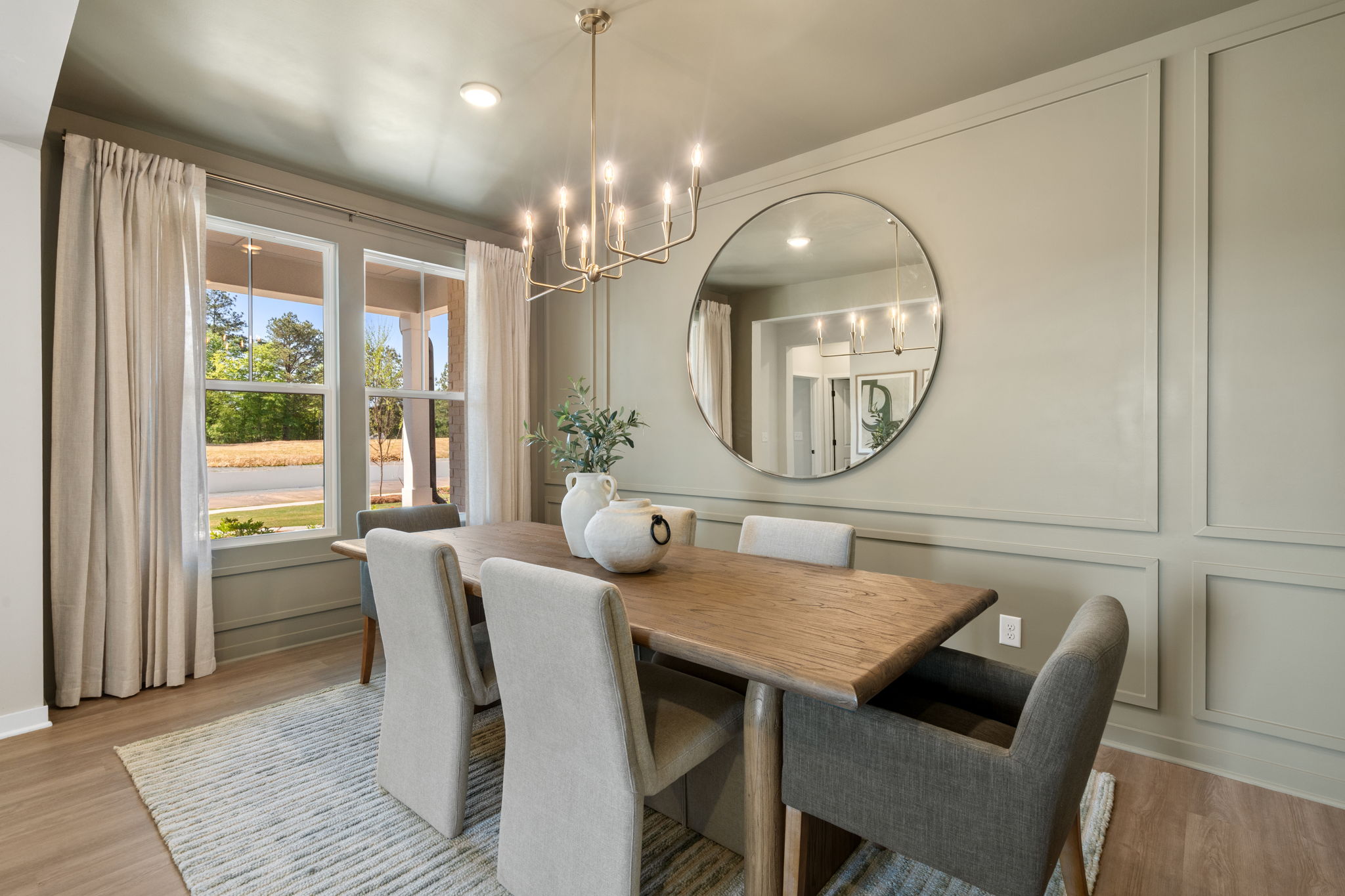 A dining room table with a mirror above it.
