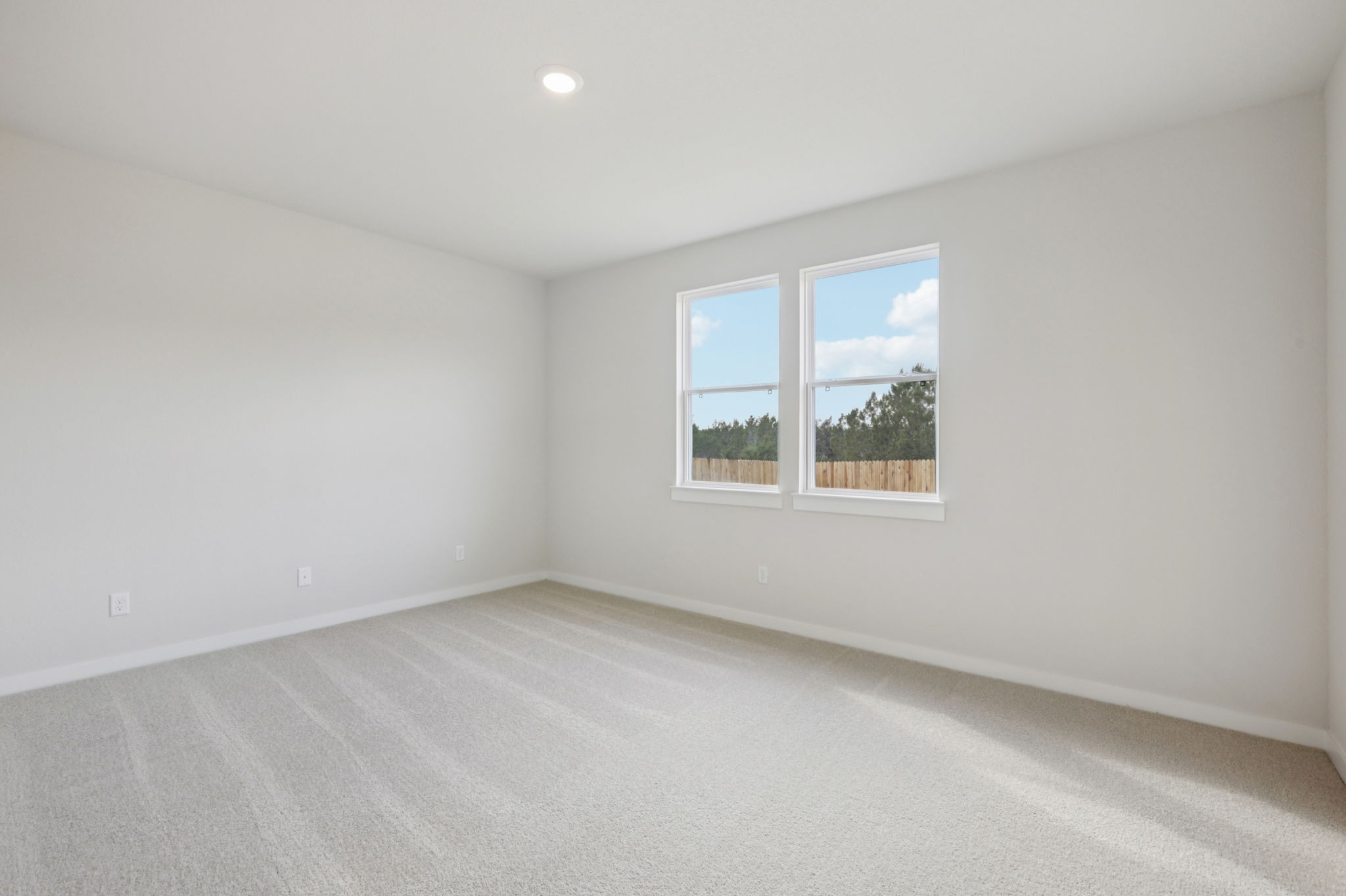 A room with a window and a white wall with a tree outside.