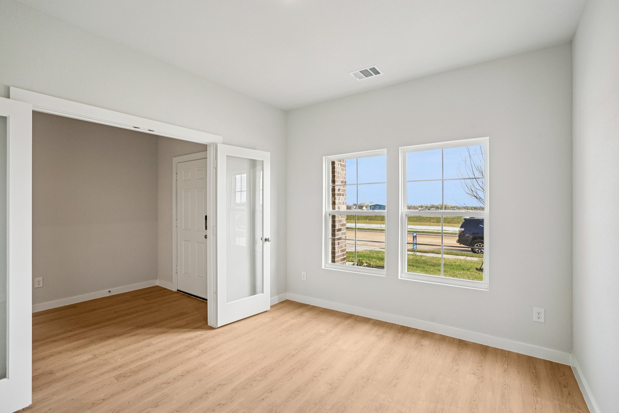 A room with a wood floor and a wood floor with a window.