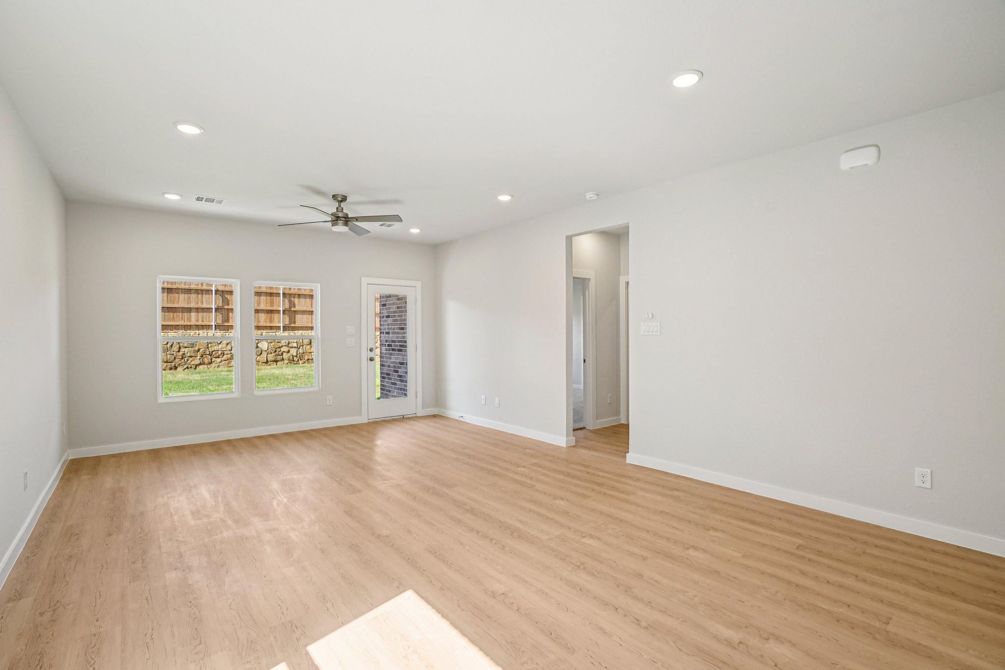 A room with a wood floor and a wood floor with a fan.