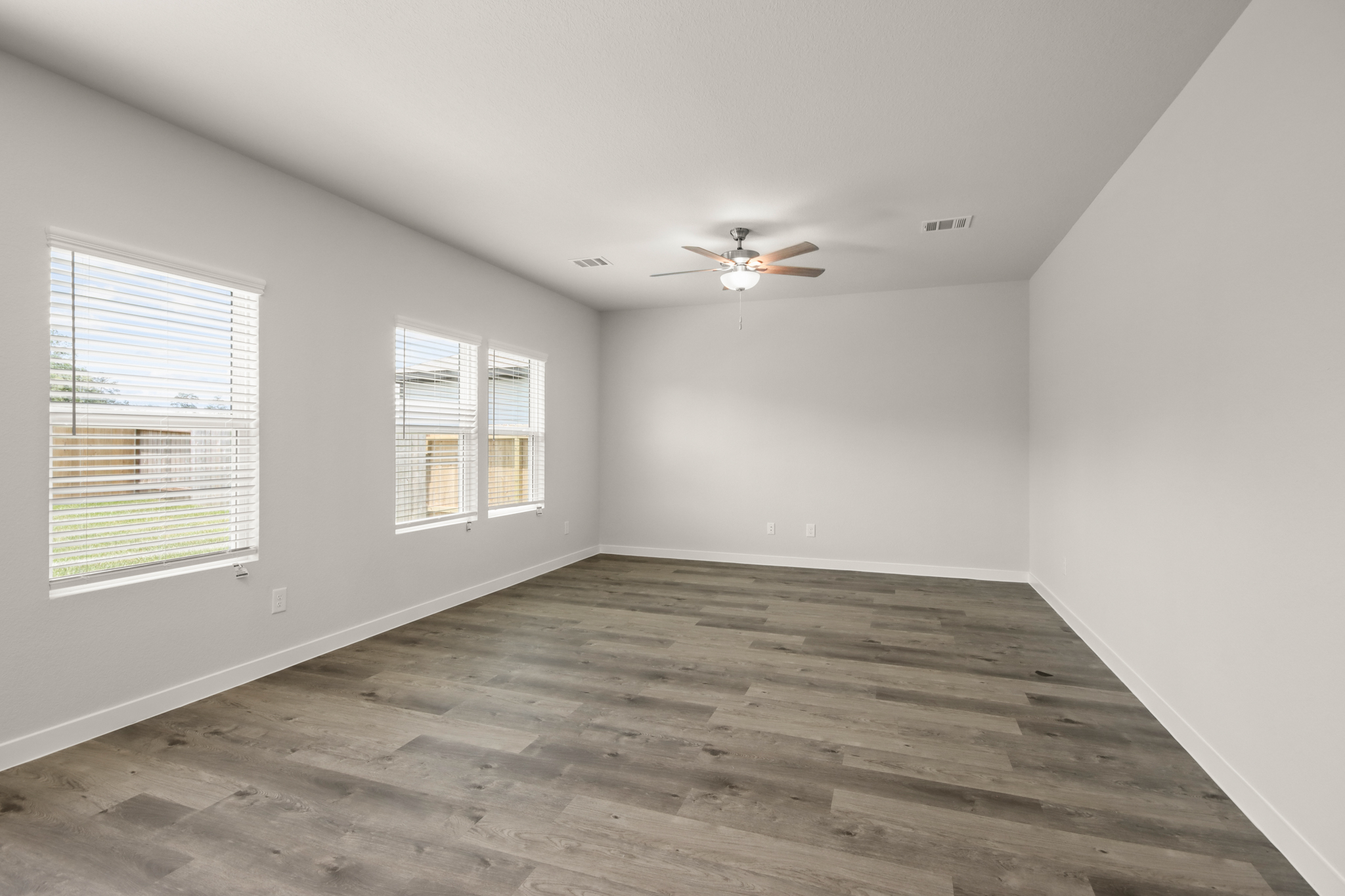 A room with a ceiling fan and windows.