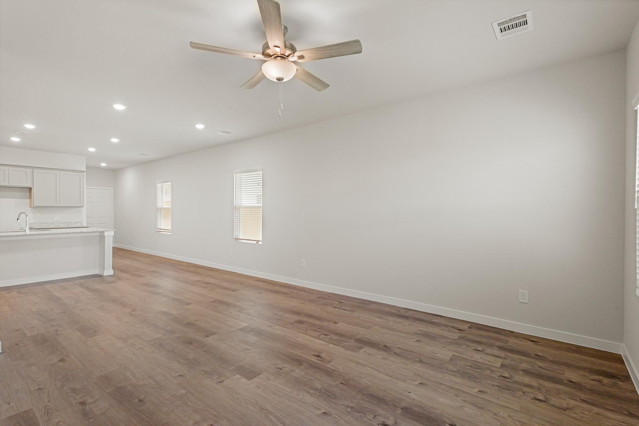A room with a ceiling fan and a wood floor.