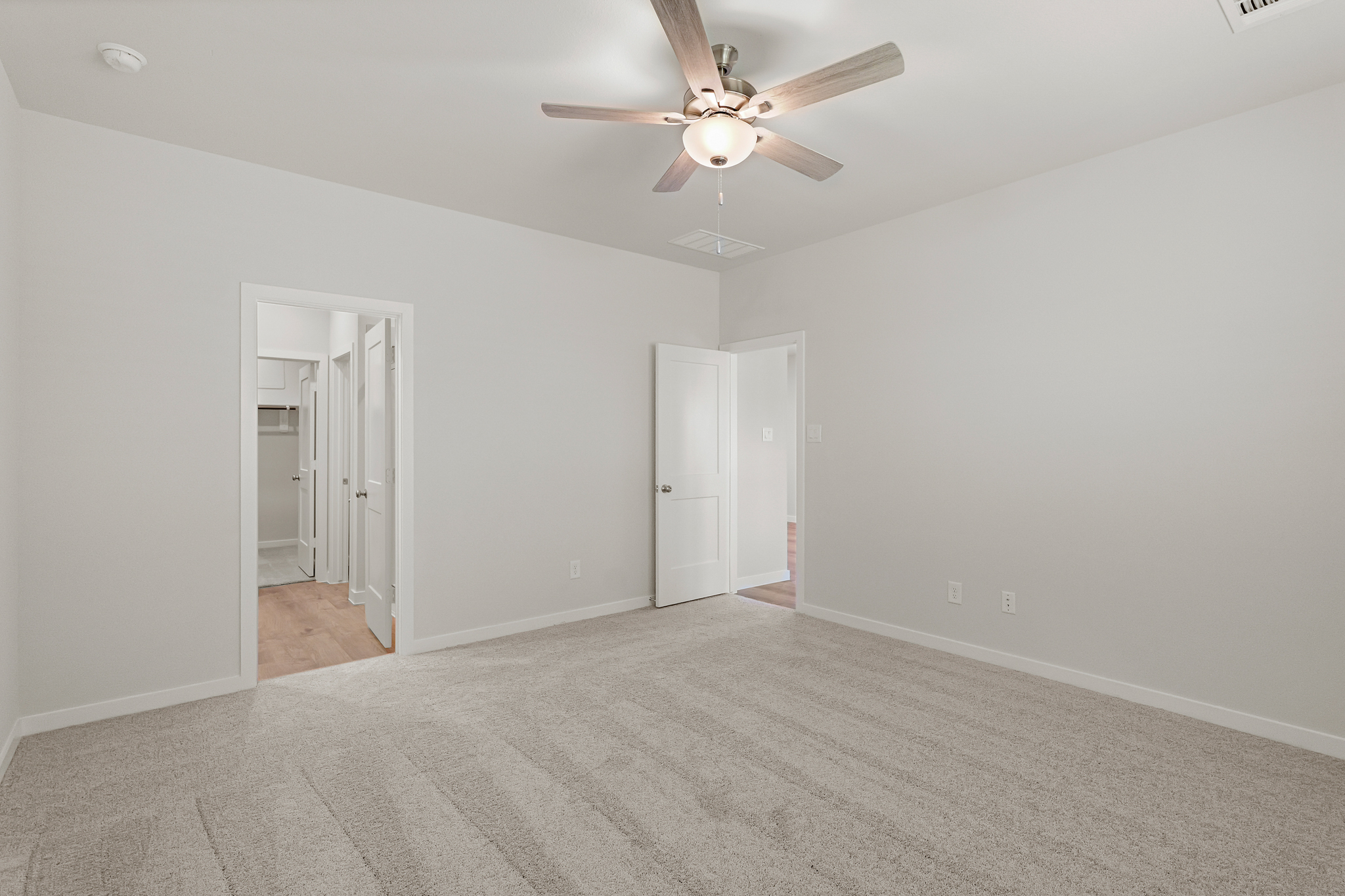 A room with a ceiling fan and white walls.