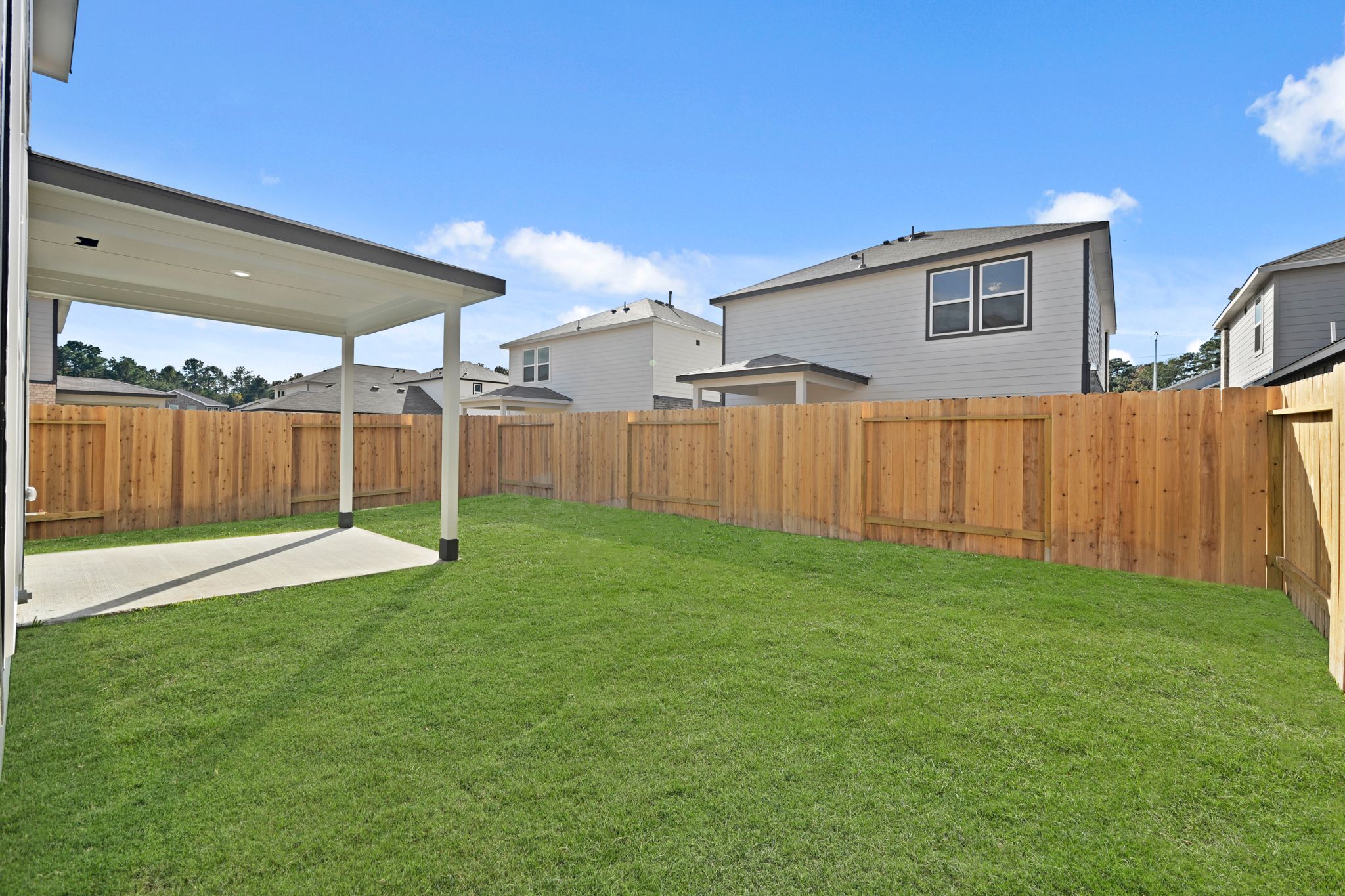 A backyard with a fence and a house.
