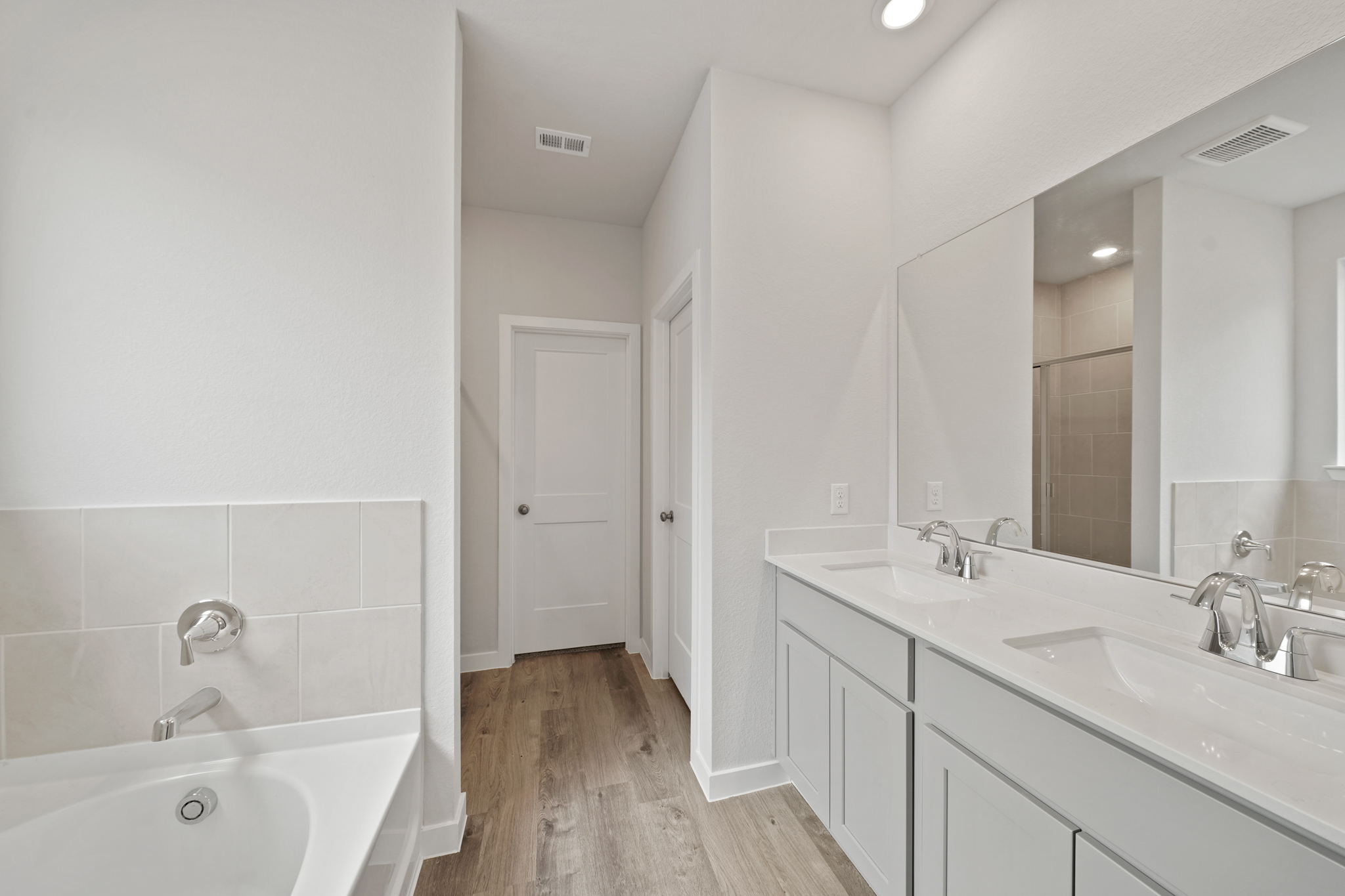 A bathroom with a tub sink and mirror.