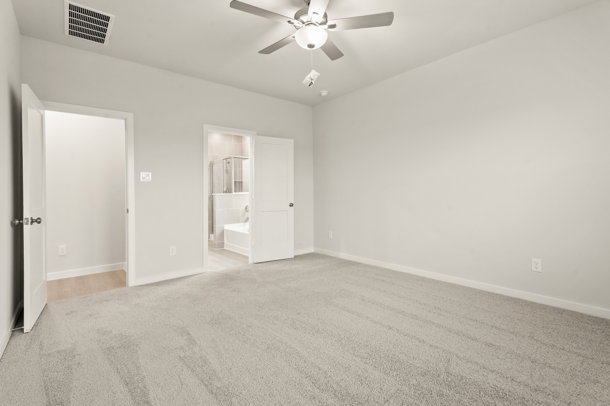 A room with a ceiling fan and a door.