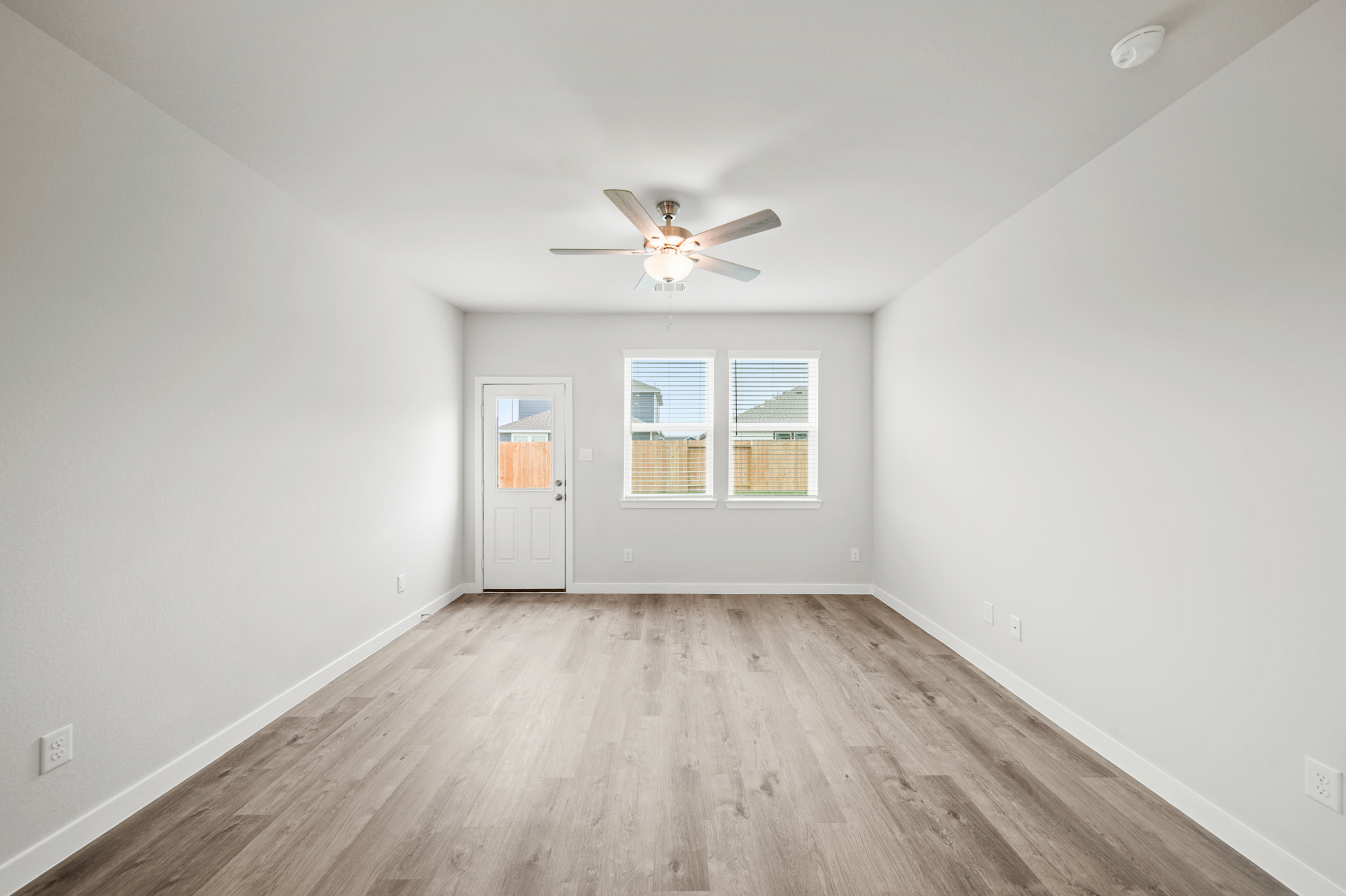 A room with a wood floor and a ceiling fan.
