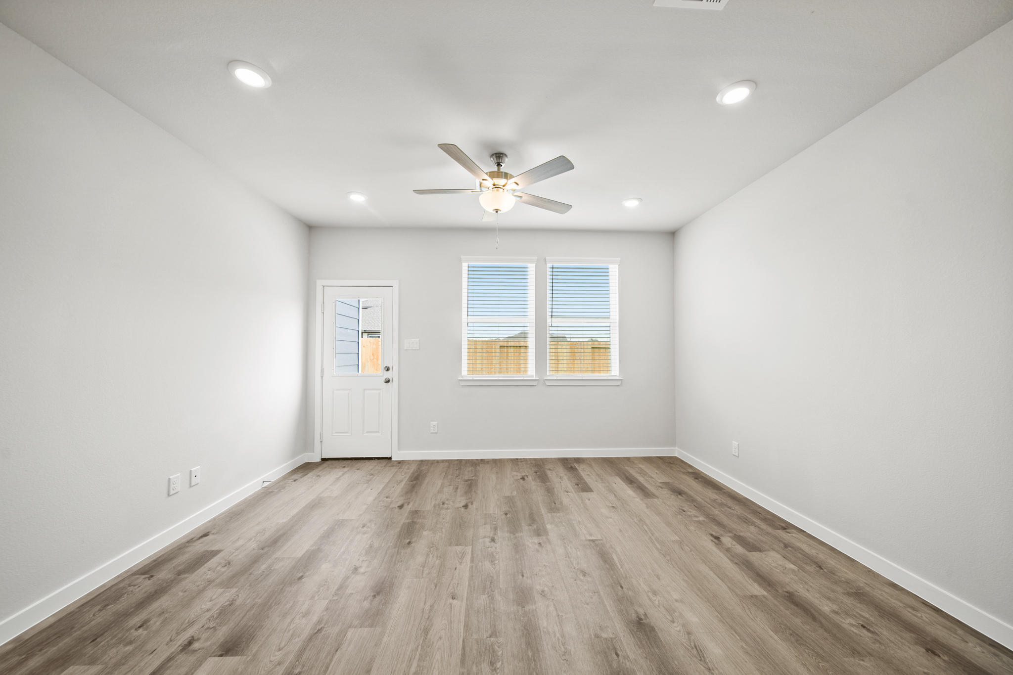 A room with a ceiling fan and a wood floor.