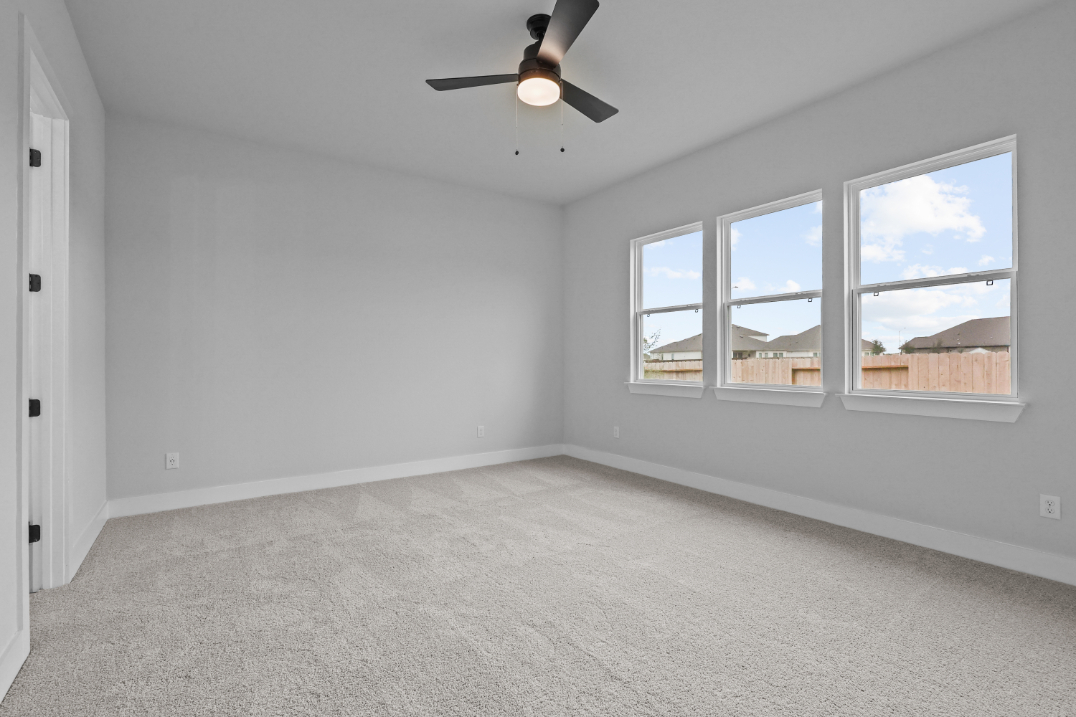 A room with a ceiling fan and a window with a view of the city.
