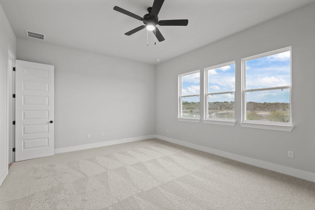 A room with a ceiling fan and a window with a view of the water.