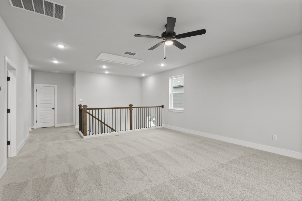 A room with a ceiling fan and a railing.