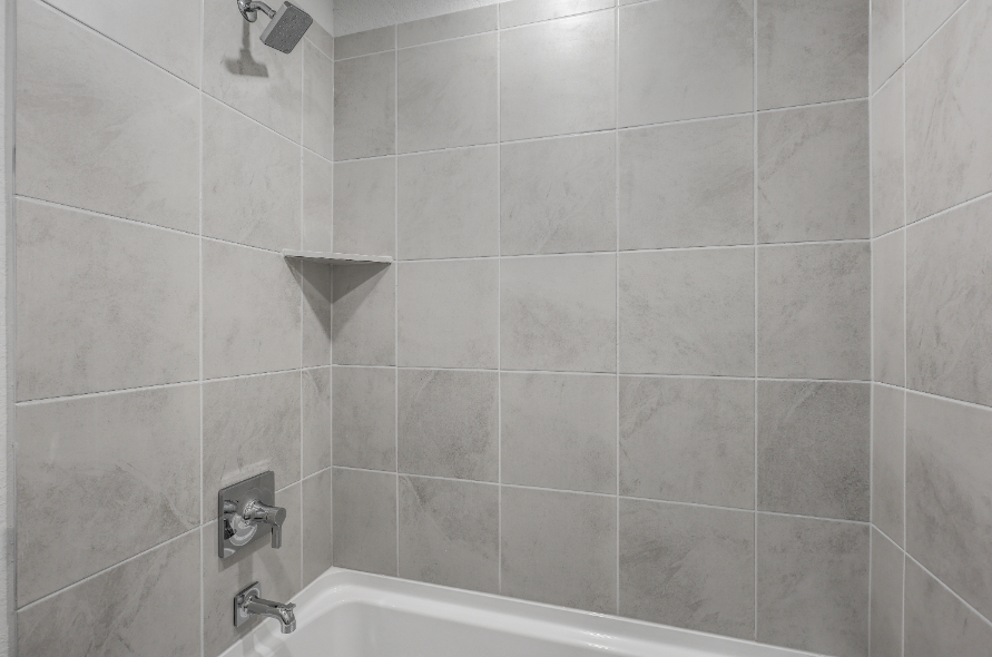 A bathroom with a bathtub and tile walls.