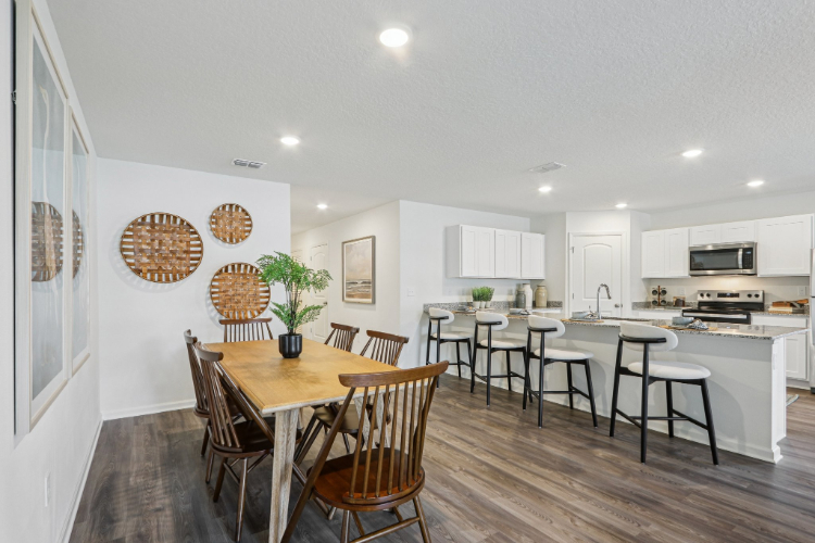A kitchen with a dining table and chairs.