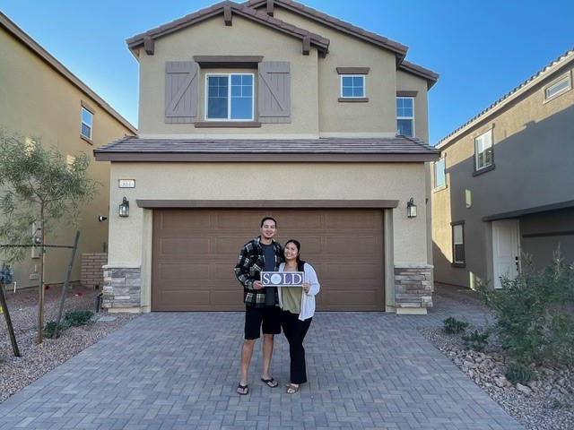 A couple of women posing for a picture in front of a house.